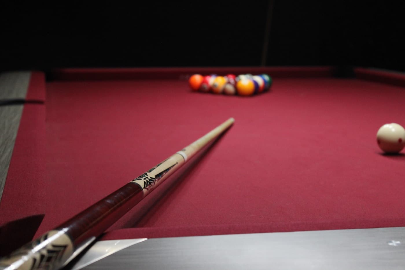 A cue laid across the felt behind a rack of balls