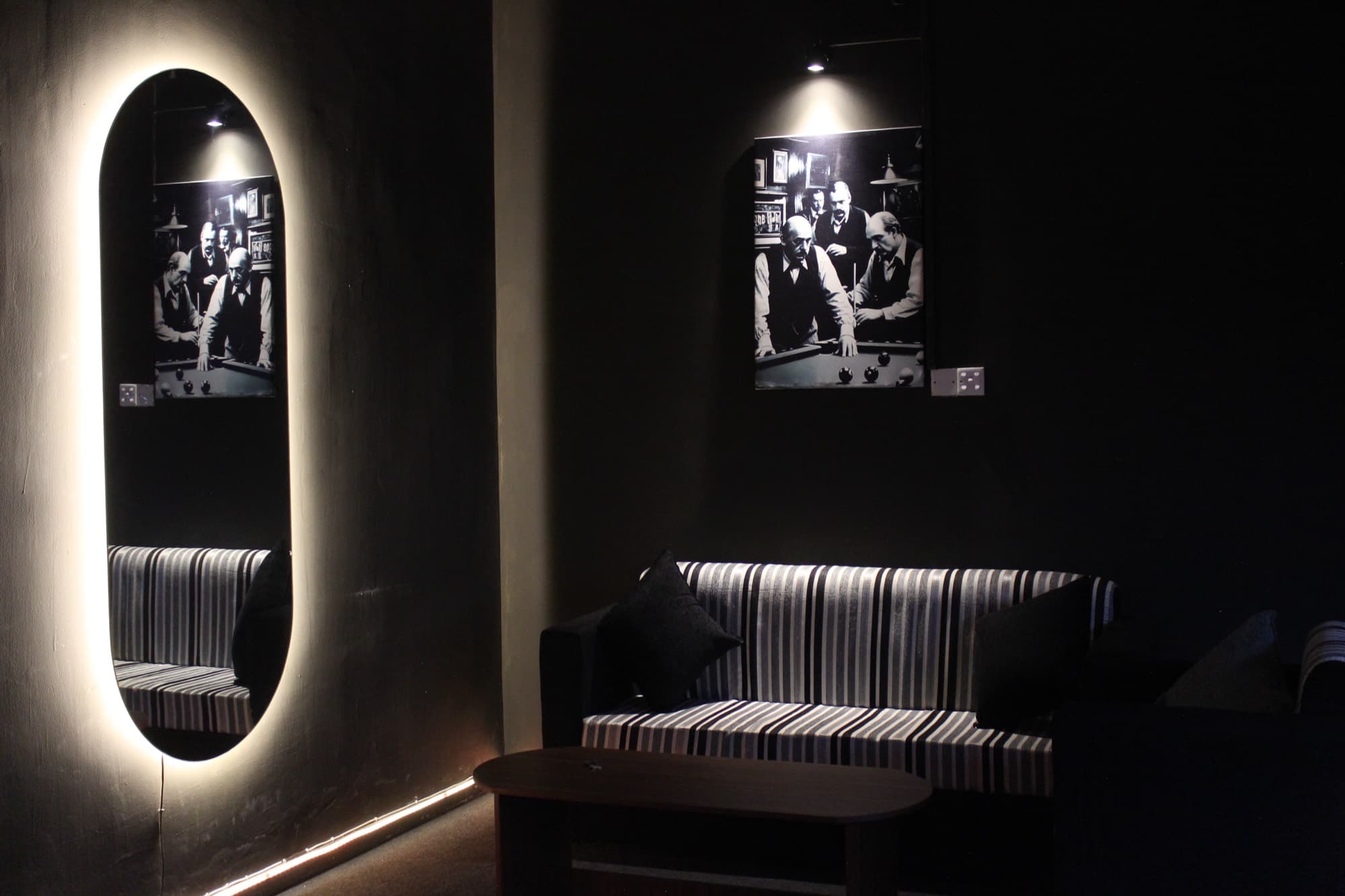 A padded banquette beside framed prints on a dark wall