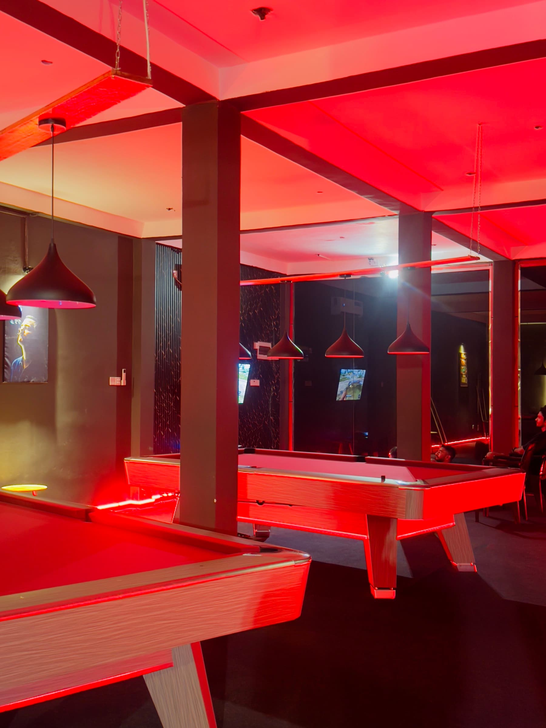 Pool tables under deep red light, lamps hung low over the felt