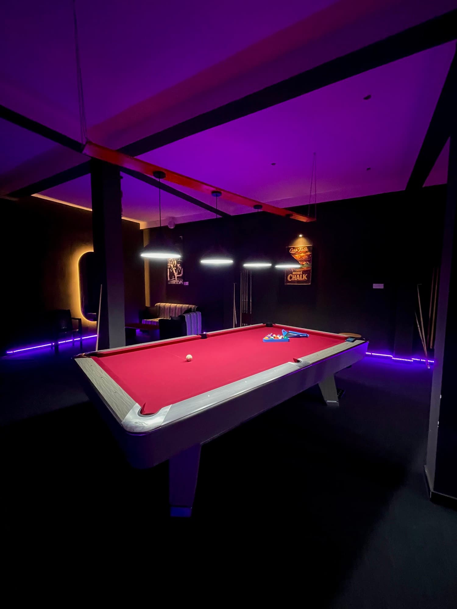 A table lit violet, cues resting across the felt